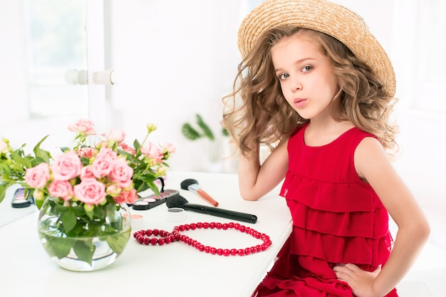 Free photo a little girl with red dress and cosmetics.