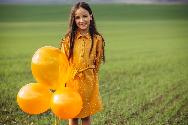 Little girl with yellow balloons in the field