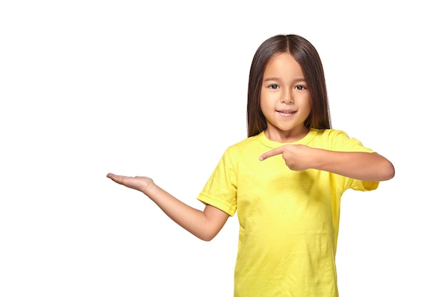 Little girl in yellow t-shirt holding her hand out and showing copy space for your product isolated on white background