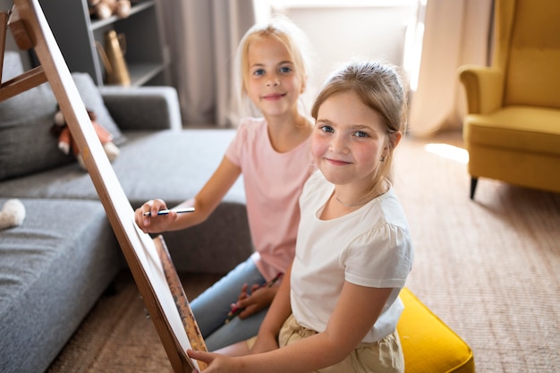 Little girls drawing using easel at home together