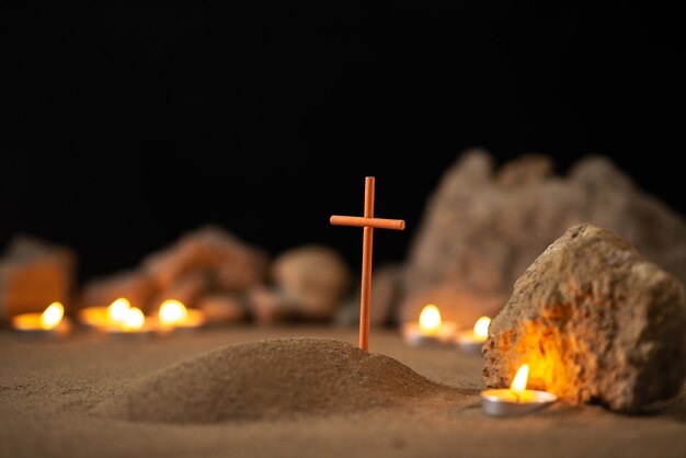 Little grave with stones and burning candles on dark surface