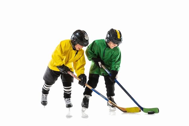 Free photo little hockey players with the sticks on ice court and white  background.