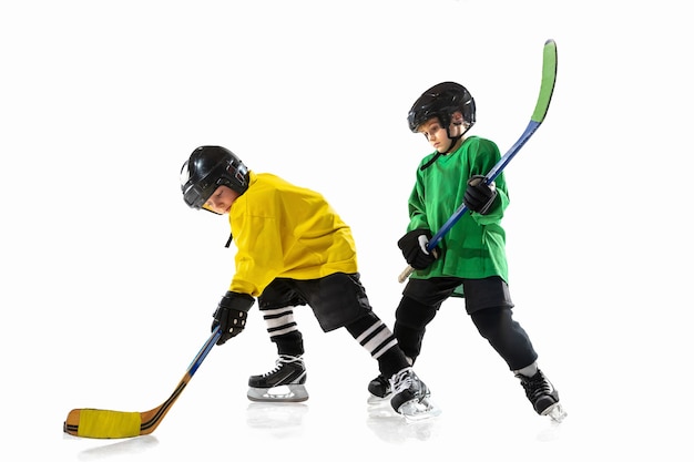 Little hockey players with the sticks on ice court and white studio wall