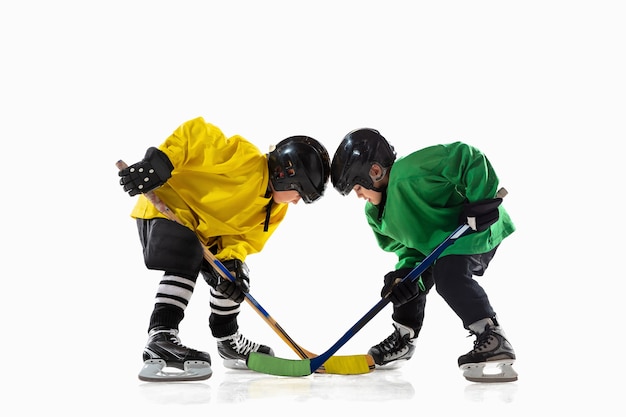 Free photo little hockey players with the sticks on ice court and white studio wall