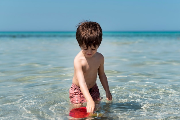 Free photo little kid playing with bucket in water