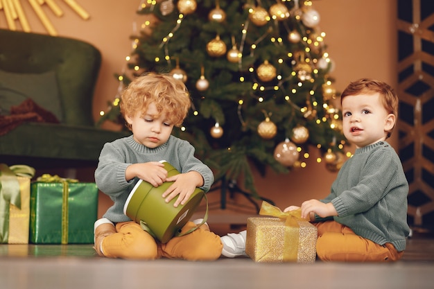 Little kids near christmas tree in a gray sweater