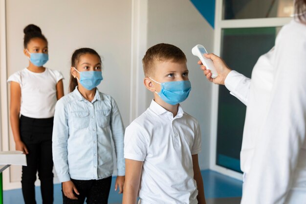 Little kids waiting in line for a teacher to take their temperature