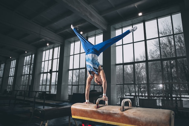 Little male gymnast training in gym, composed and active.