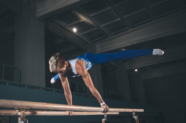 Little male gymnast training in gym flexible and active Caucasian fit little boy athlete in sportswear practicing in exercises for strength balance