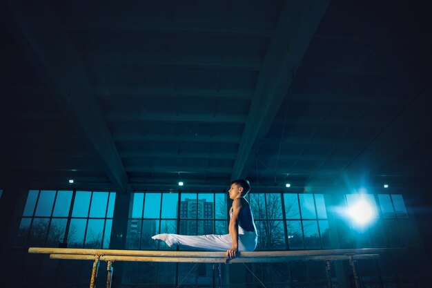 Little male gymnast training in gym, flexible and active