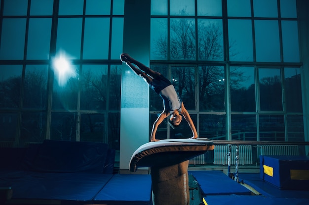 Free photo little male gymnast training in gym flexible and active