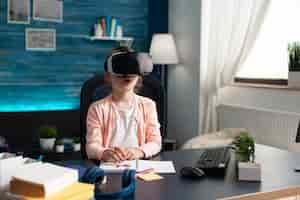 Free photo little pupil at home desk using vr glasses for class