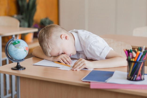 Free photo little pupil laying on table in classroom