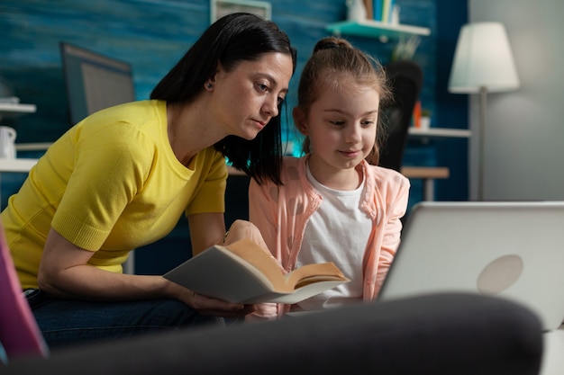 Free photo little pupil using laptop for homework and mom assisting