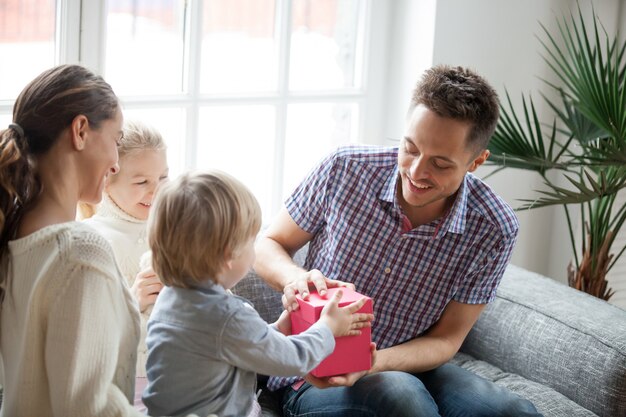 Little son presenting gift for dad, family celebrating fathers day