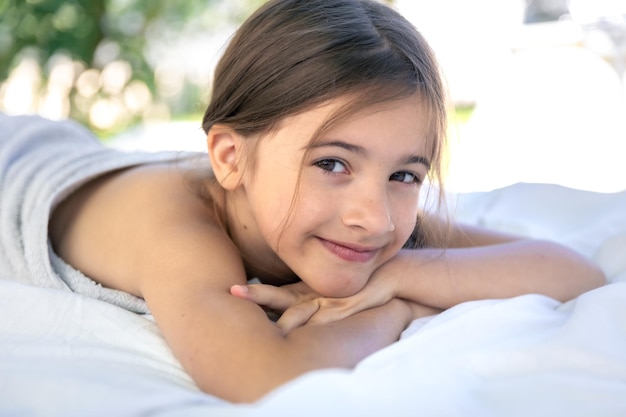 Free photo a little teenage girl is resting lying on a white sheet outside