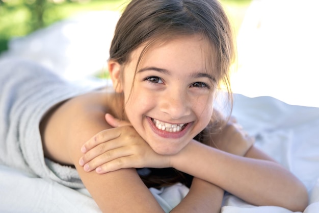 Free photo a little teenage girl is resting lying on a white sheet outside