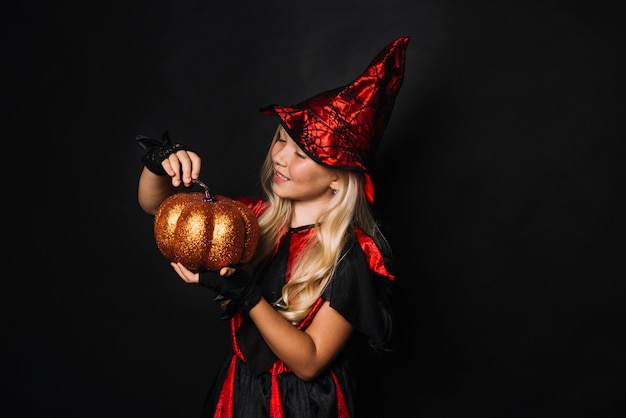 Free photo little witch looking at pumpkin