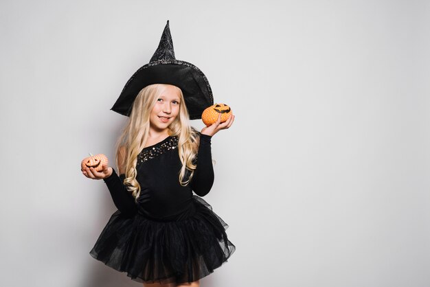 Free Photo little witch posing with jack-o-lanterns