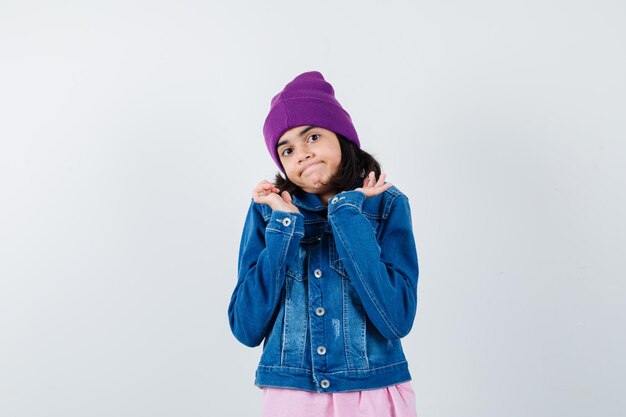 Little woman in t-shirt denim jacket beanie spreading palms out looking helpless 