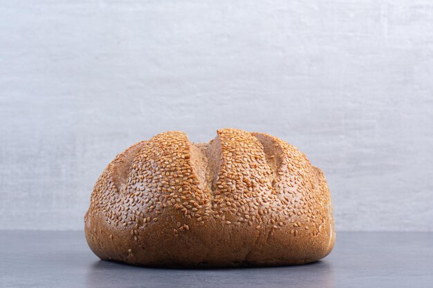 Loaf of bread covered in sesame seeds on marble background. High quality photo