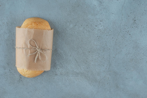 Loaf of bread tied with rope on marble surface.