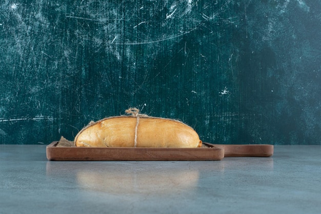 Loaf of bread tied with rope on wooden board.