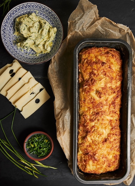 Free Photo loaf of cheese bread with herbal butter on a wooden plate with herbs