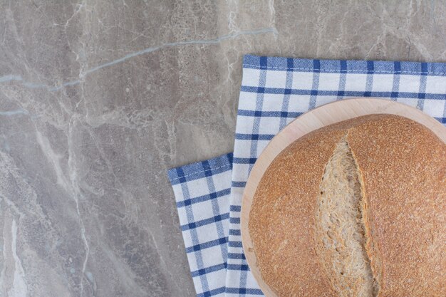 Loaf of fresh brown bread on tablecloth