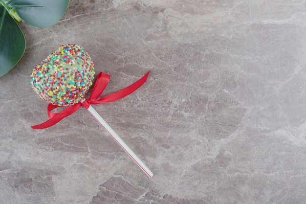 A lollipop and a decorative leaf on marble 