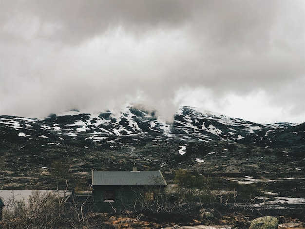 Lonely cabin stands before the mountains covered with snow