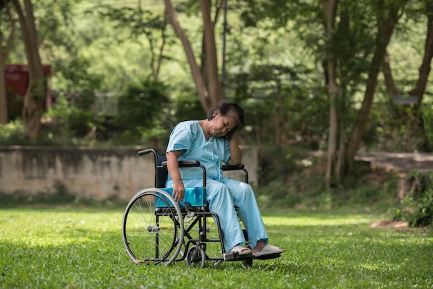 Lonely elderly woman sitting sad feeling on wheelchair at garden in hospital