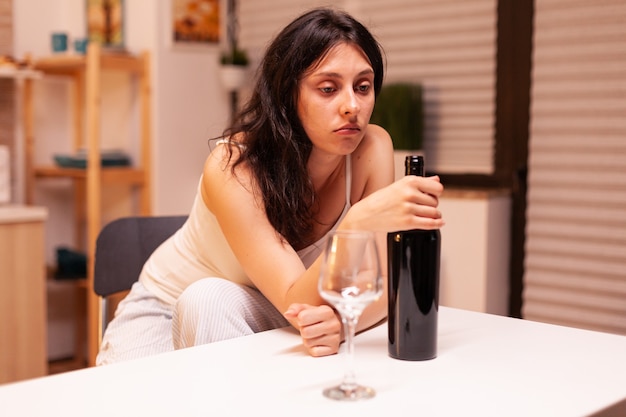 Free photo lonely woman holding a bottle of red wine