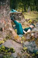 Free photo lonely young female sleeping by a tree and next to rock formations