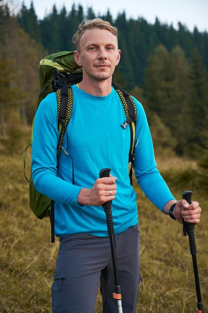 Lonely young man hiking with backpack outdoors