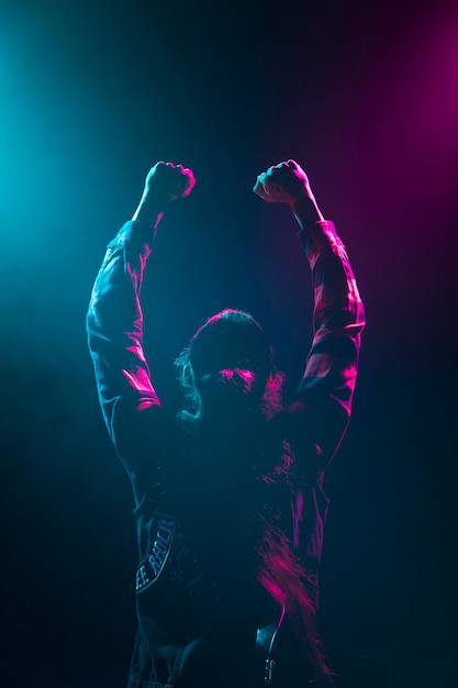 Free Photo long hair artist holding hands in the air on stage