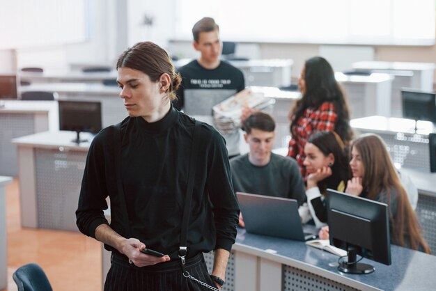 Long haired guy. Group of young people in casual clothes working in the modern office