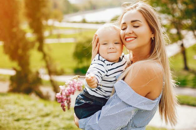  long-haired mom in a blue dress standing in a solar park and holding her baby