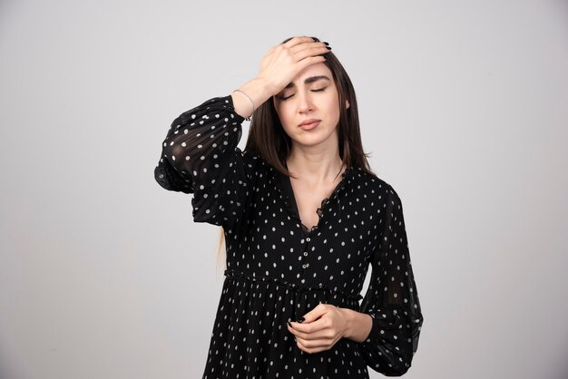 Long haired woman in black dress having headachr.