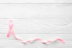 Free photo long pink ribbon on wooden background