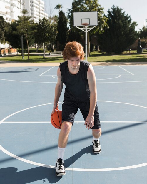 Long shot of boy playing basketball