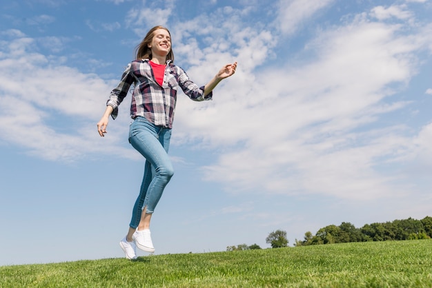 Long shot cheerful girl running on grass