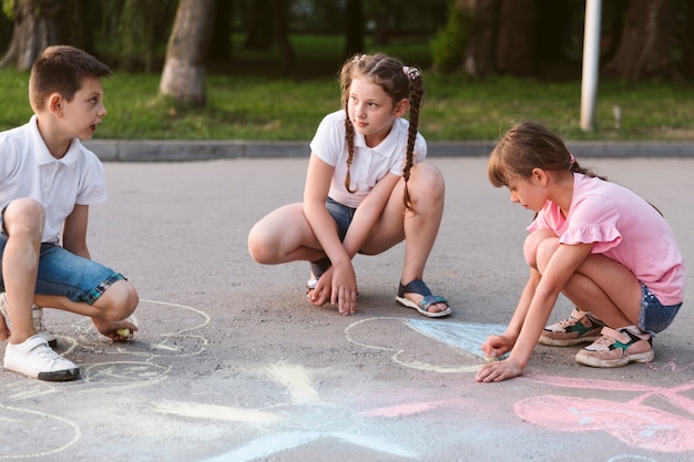 Long shot children drawing with chalk