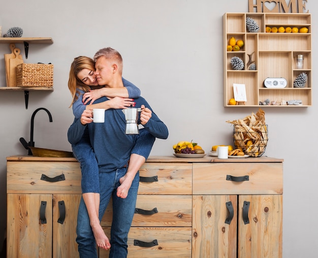 Long shot couple hugging in the kitchen