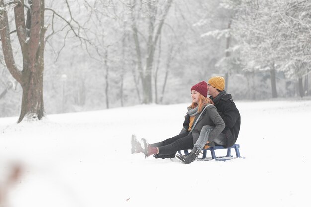 Long shot of couple playing with sleigh in the snow