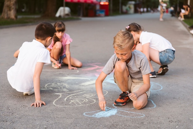 Free photo long shot friends drawing with chalk