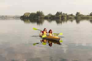 Free photo long shot friends rowing in kayak