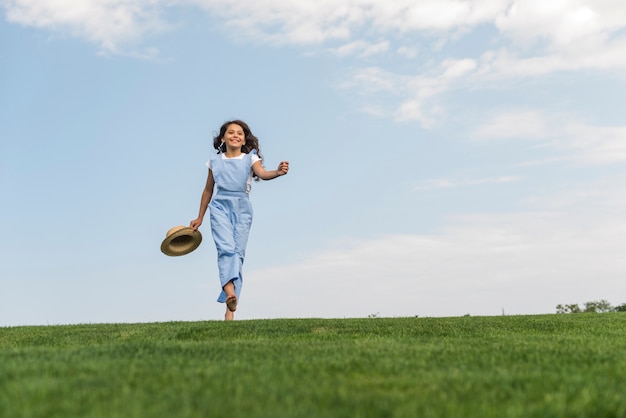 Long shot girl walking barefoot on grass