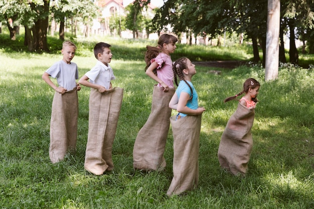 Long shot girls and boys running in burlap bags