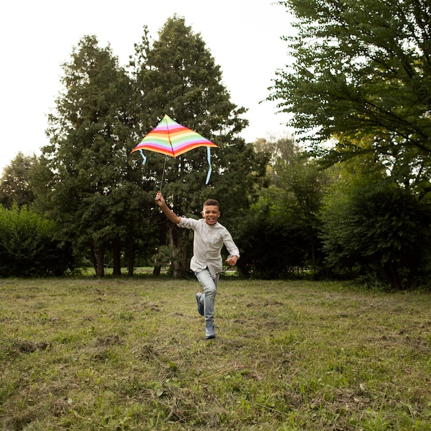 Free photo long shot of happy boy having fun with a kite